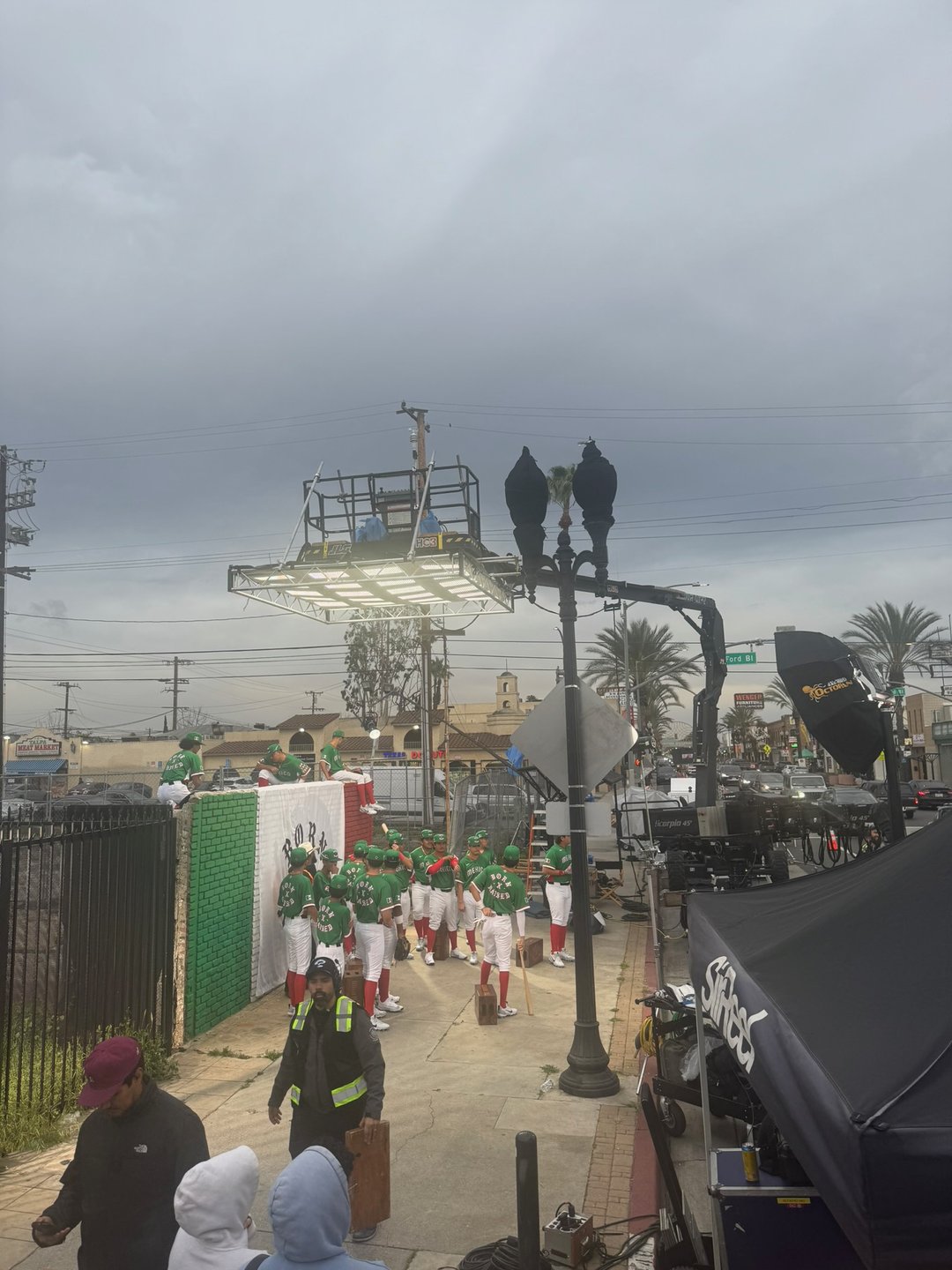 Behind the scenes on the Born x Raised spot, a Collective Camera Cranes rig lifting an overhead light array above a baseball team on an East LA street