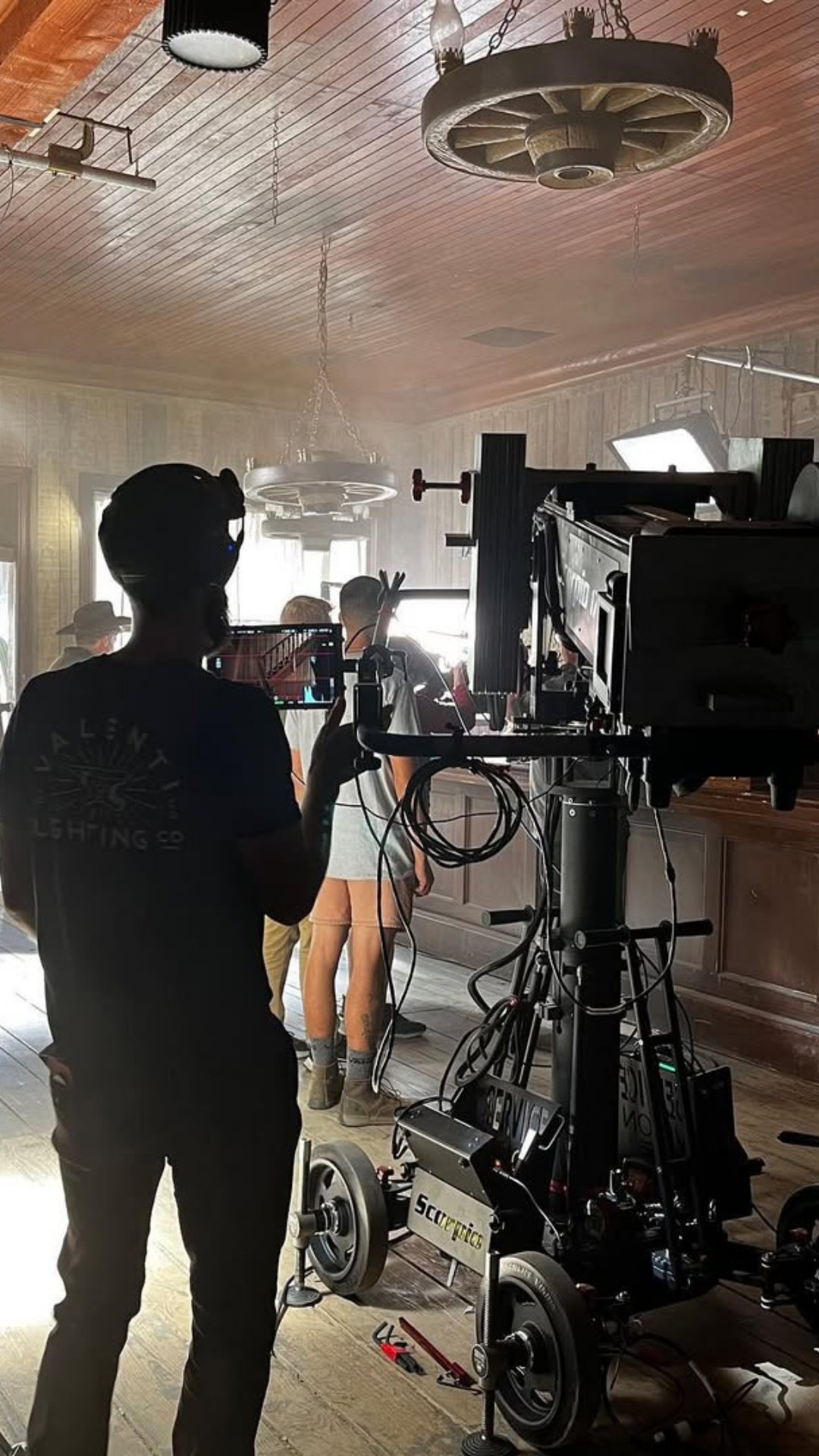 A Collective Camera Cranes crane arm counterweighted on a period interior set, operator silhouetted at the monitor