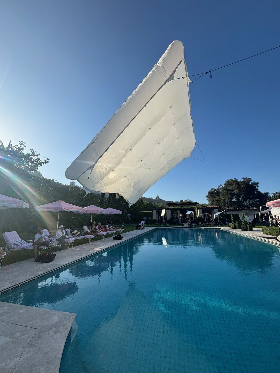 A Legacy Grip overhead silk suspended above a pool on the Old Navy commercial, softening midday sun