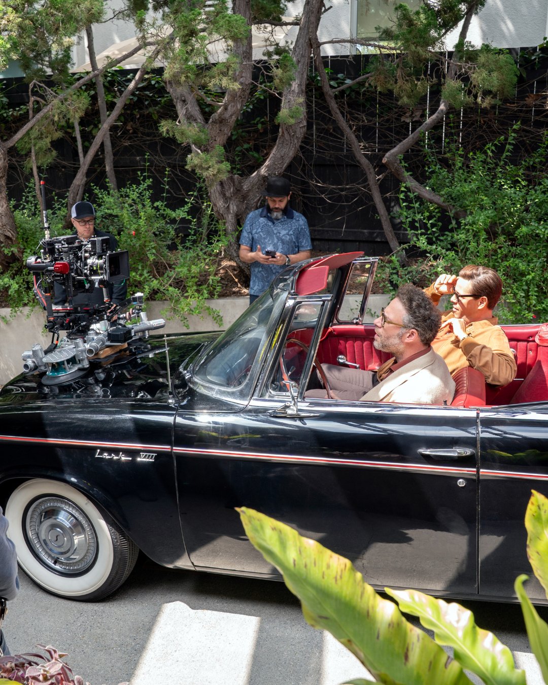 Behind the scenes on The Studio, a camera car rig mounted to a vintage convertible with two actors in the front seat